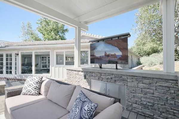 Outdoor lounge area with a mounted television and comfortable seating