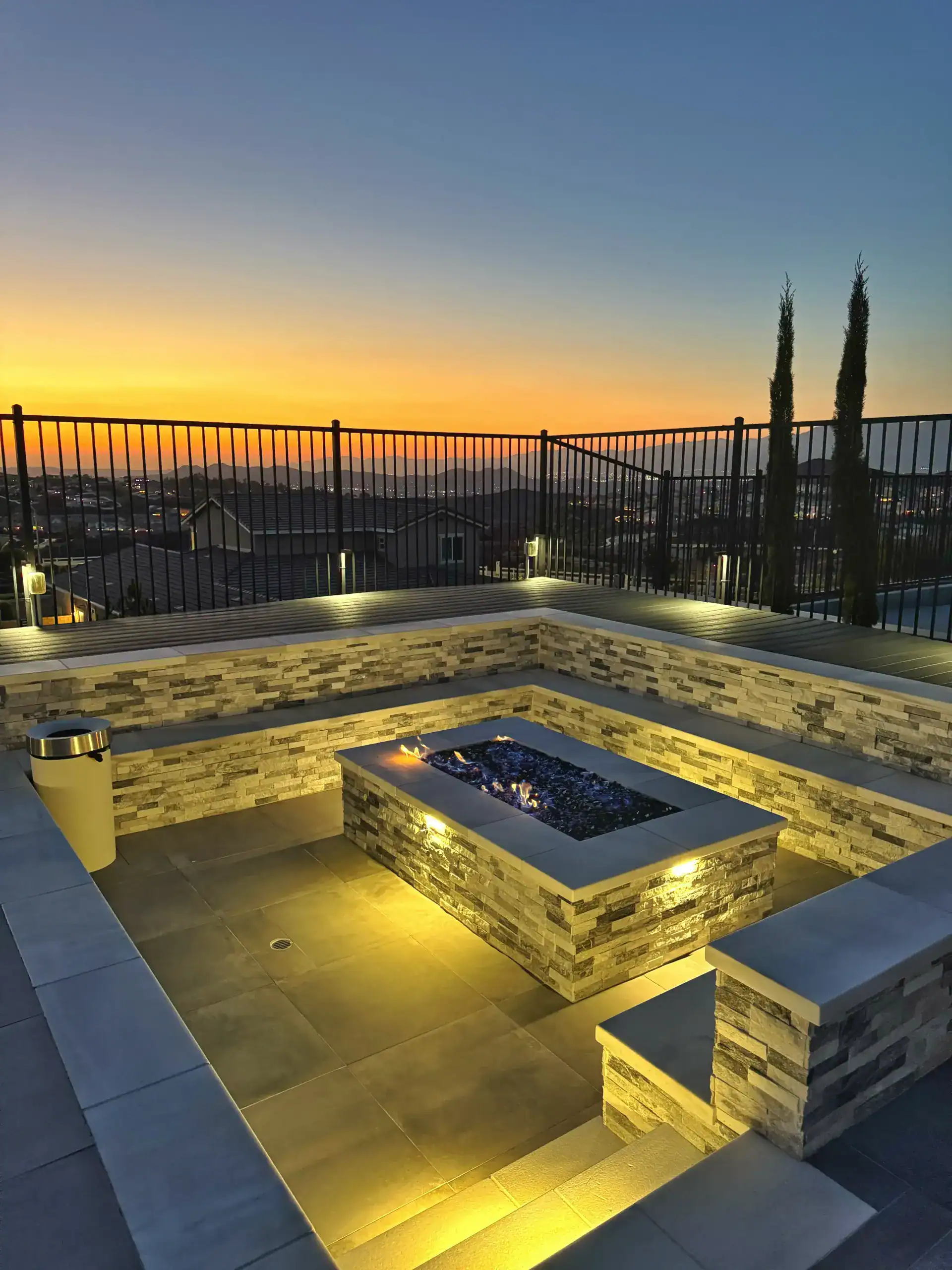 Ecoworkz rooftop patio with stone fire pit, built-in seating, and outdoor lighting at sunset