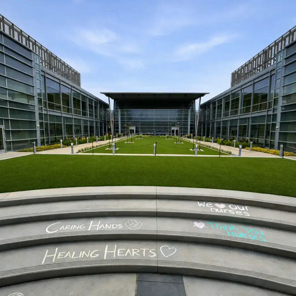 An artificial grass lawn within a modern medical facility courtyard,