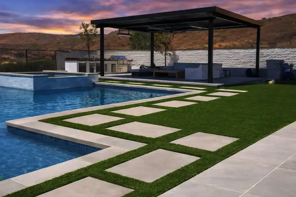 Poolside artificial turf with paver walkway leading to a covered pergola lounge area