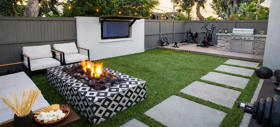 Backyard outdoor living space with artificial turf, fire pit, BBQ island, paver walkway, and seating area.