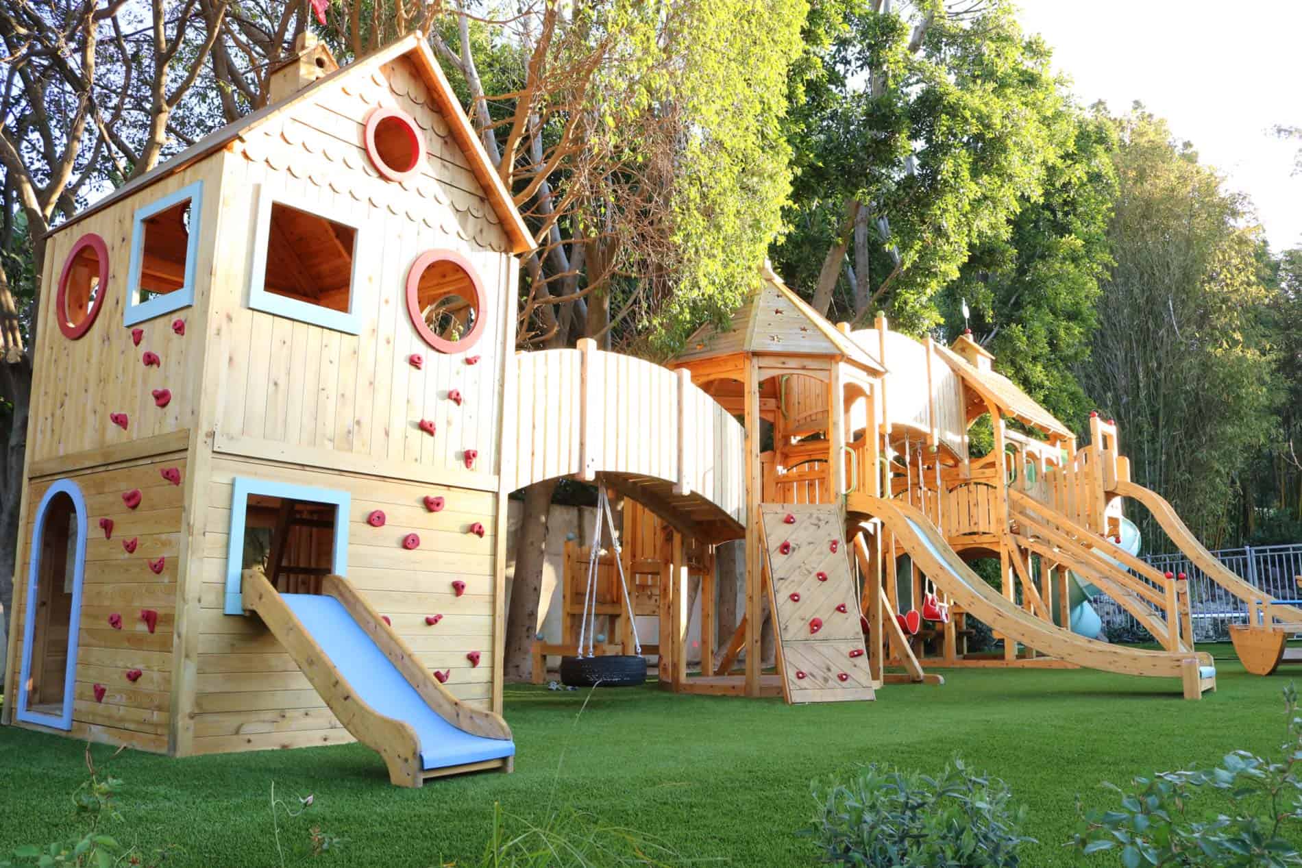 Ecoworkz backyard playground with wooden play structure, slides, and artificial turf surface