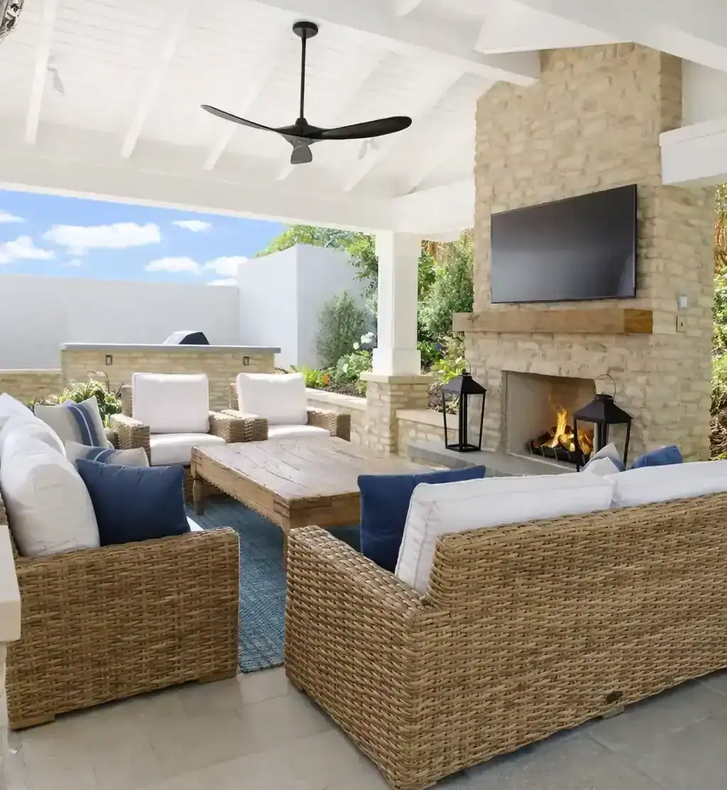 covered outdoor living patio with wicker seating, fireplace, and mounted TV for backyard entertainment