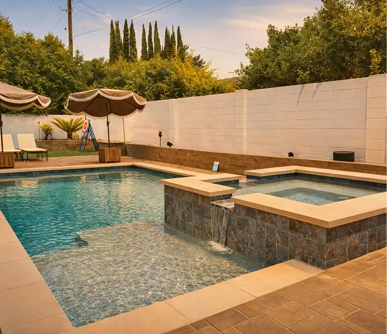 Modern swimming pool with raised spa, tanning ledge, waterfall feature, and poolside relaxation area.